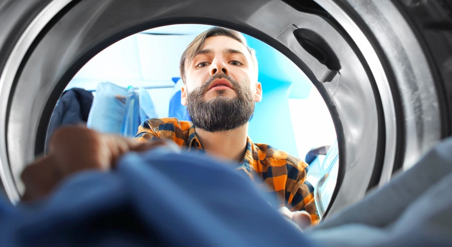 Un homme récupère du linge sec et chaud dans un sèche linge condensation