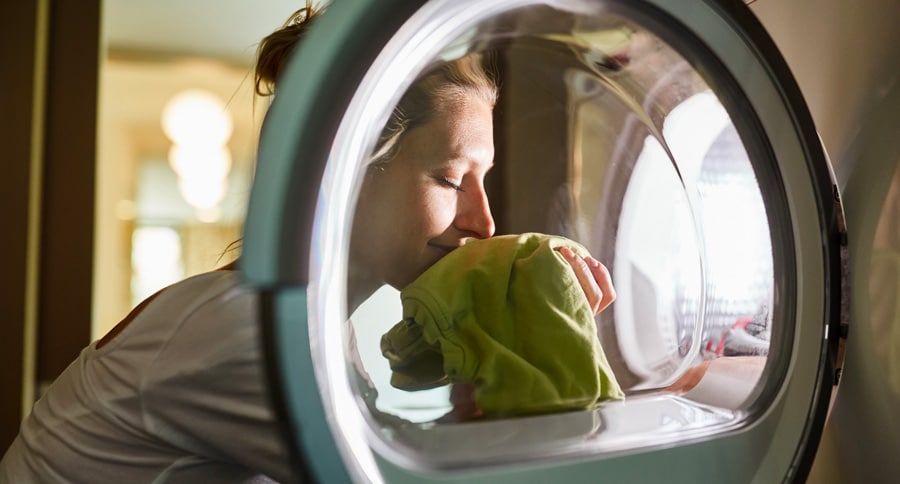 Une jeune femme est heureuse du parfum enivrant de son linge sec 